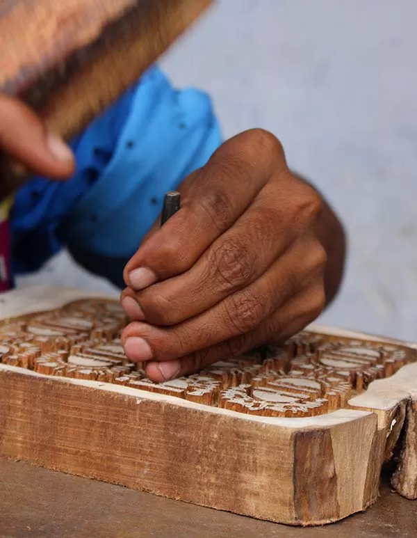 Un artisan en train de graver un block d'impression en bois.
